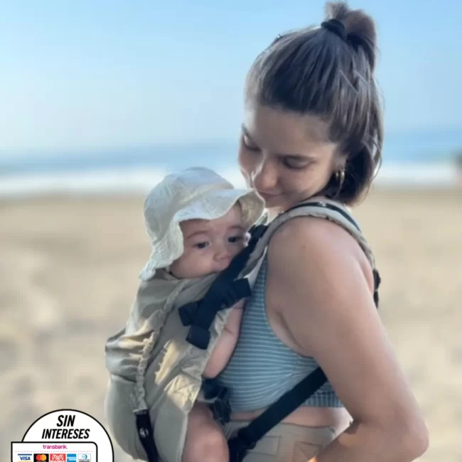 madre con bebe en portabebe ergonomico en playa de mexico