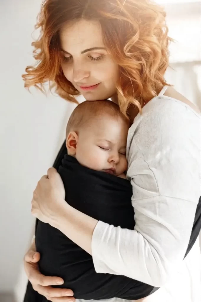 Madre usando portabebés ergonómico para calmar cólicos de bebé